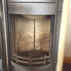 Innenansicht eines Ofens mit sichtbaren Schamottsteinen, die von Ruß und Asche bedeckt sind.