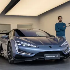 Hombre posa junto al deportivo BYD Yangwang U9, con diseño futurista y luces LED llamativas.