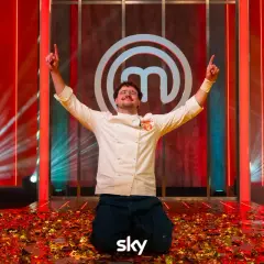 Vincitore del finale MasterChef 2026 in ginocchio tra coriandoli dorati, con le braccia alzate e il logo di MasterChef sullo sfondo.