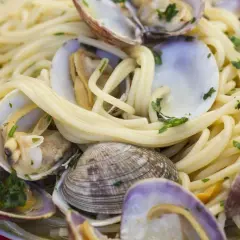 Un piatto invitante di spaghetti alle vongole, con pasta dorata e molluschi freschi, guarnito con prezzemolo tritato.