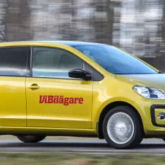 Gul Volkswagen Up körs på en väg, med texten "ViBilägare" på sidan. En potentiell vw up problem kan vara att den är för liten för familjen.