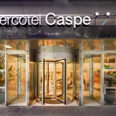Entrada principal del Sercotel Caspe, con puerta giratoria y letrero luminoso.