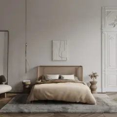 Elegancka sypialnia z łóżkiem z rattanowym zagłówkiem, dywanem i ozdobnymi drzwiami z bogatą sztukaterią w sypialni.