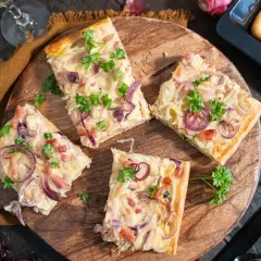 Saftiger Zwiebelkuchen vom Blech, belegt mit roten Zwiebeln und Speck, garniert mit Petersilie.