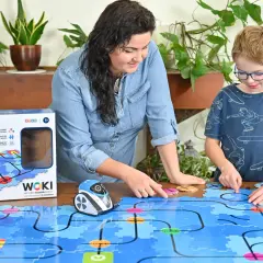 Mama i syn bawią się robotem WOKI, ucząc się kodowania dla 6 latka. Kolorowe klocki tworzą labirynt.