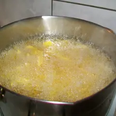 Frytki smażące się w głębokim oleju w metalowym garnku.