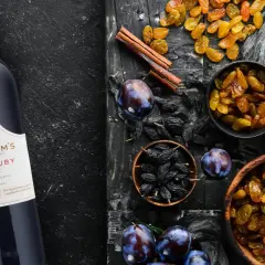 Butelka Graham's Fine Ruby Port obok bakalii: rodzynek, śliwek, czekolady i cynamonu. Idealny do deserów, porto ile procent?