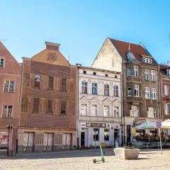 Kamienice Starego Miasta w Olsztynie z widocznym placem i zieloną hulajnogą.