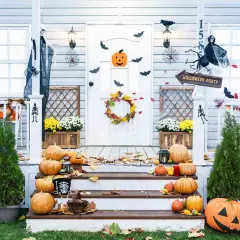 Porche decorado para Halloween con calabazas, telarañas, murciélagos y un esqueleto.