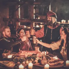 Ludzie w strojach z epoki wznoszą toasty przy suto zastawionym stole. Kto wymyślił piwo? Może jeden z nich?