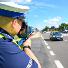 Policjant mierzy prędkość pojazdu, aby ustalić taryfikator punktów karnych.