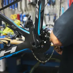 Mechanik dokonuje regulacji przedniej przerzutki w rowerze szosowym. Widać korbę Ultegra i ramę BH.