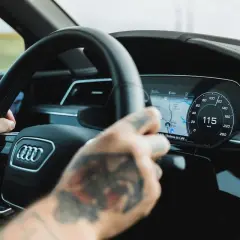 Ręce na kierownicy Audi A9, cyfrowy kokpit pokazuje 115 km/h.
