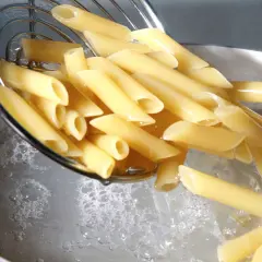 Penne vengono versate in acqua bollente. Il giusto quanto sale nella pasta è fondamentale per un sapore perfetto.