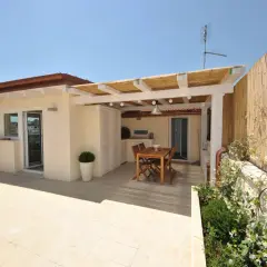 Un terrazzo sul tetto con tavolo in legno, pergola di bambù e vista sulla città. Ideale per cene all'aperto.