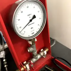 Manometr wskazuje ciśnienie podczas próby szczelności instalacji gazowej. Urządzenie jest częścią czerwonej skrzynki narzędziowej.