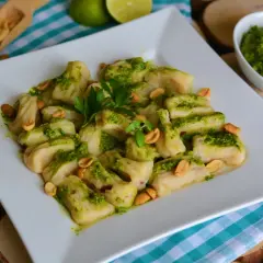 Pyszne gnocchi z pesto, posypane orzeszkami ziemnymi i udekorowane natką pietruszki. Idealne danie dla miłośników włoskich smaków.