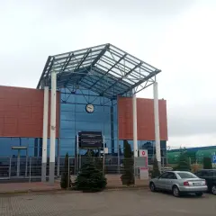 Nowoczesny budynek kolejowy w Terespolu, z charakterystycznym szklanym dachem i brązowymi panelami. W tle widać zielone wagony towarowe, a przed budynkiem zaparkowane samochody. To ważny punkt na trasie Terespol-Brześć.