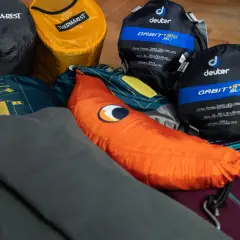 Śpiwory Deuter, karimata Thermarest i pomarańczowa poduszka – to wszystko, co zabrać pod namiot na nocleg w plenerze.