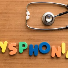 Kolorowe litery układają się w napis "DYSPHONIA", a obok leży stetoskop. To symbol problemów ze struny głosowe inaczej.