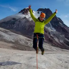 Radosny alpinista skacze na lodowcu pod Kazbekiem w Gruzji.