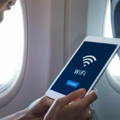 Osoba w samolocie sprawdza na tablecie, czy w samolocie Ryanair jest wifi. Widoczny przycisk "Connect".