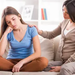 Nastolatka zamyślona, mama kładzie jej rękę na ramieniu, wspierając w trudnych zachowaniach nastolatków w okresie dojrzewania.
