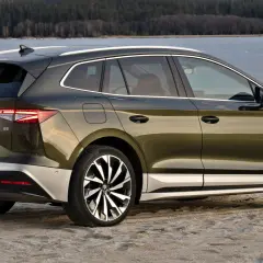 Zielony Skoda Enyaq na plaży, z widokiem na zamarznięte jezioro. Poznaj skoda enyaq wymiary i jego przestronne wnętrze.
