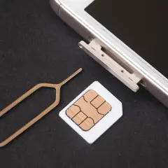 Narzędzie do otwierania tacki SIM i karta SIM obok telefonu. Dowiedz się, jak odblokować kartę SIM, aby móc korzystać z telefonu.