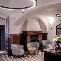 Eleganckie fotele SPA, kominek i bukiet kwiatów w przytulnym wnętrzu.