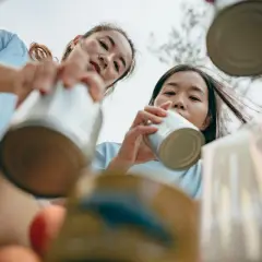 Two young women participate in DEI volunteer opportunities, sorting cans for recycling.