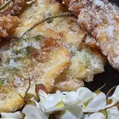 Délicieux beignets d'acacia, croustillants et saupoudrés de sucre, accompagnés de fleurs blanches.
