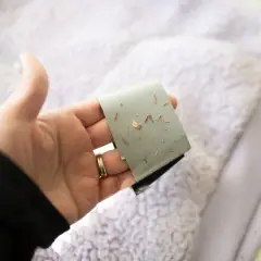 Main tenant une bande adhésive couverte de petits débris, pour montrer comment enlever un flocage sur un kway.