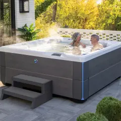 Para relaksu w ogrodzie: para cieszy się gorącą kąpielą w nowoczesnych wannach spa ogrodowych, otoczonych zielenią i słońcem.