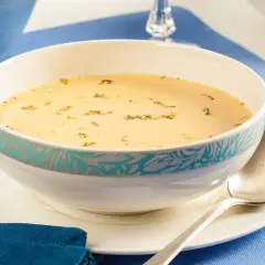 Aksamitna zupa cytrynowa, ozdobiona ziołami, czeka na łyżkę.