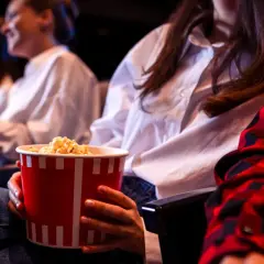 Ludzie w kinie jedzą popcorn. Zastanawiasz się, ile kosztują nachosy w kinie?