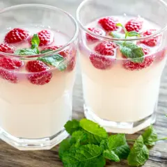 Dwa kieliszki orzeźwiającego prosecco z malinami i listkami mięty. Idealne na letnie popołudnie.