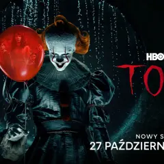 Pennywise z czerwonym balonem na tle mrocznego kanału. Napis "TO".