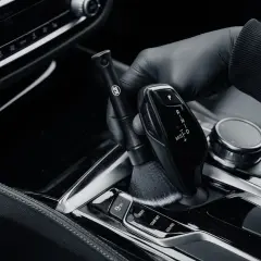 Rękawiczka z delikatną szczoteczką czyści błyszczące piano black wokół dźwigni zmiany biegów.