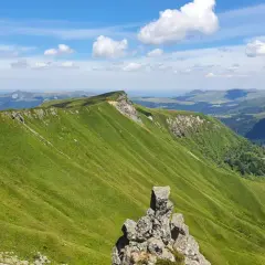 Zielone, faliste wzgórza Masywu Centralnego we Francji pod błękitnym niebem z chmurami.