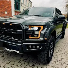 Mroczny Ford F-150 Raptor z pomarańczowymi światłami dziennymi, gotowy na przygodę.