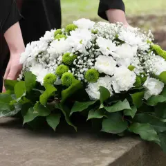 Piękne dekoracje z chryzantem na Wszystkich Świętych, ułożone z troską na kamiennym postumencie.