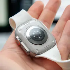 Naprawa smartwatcha Apple Watch Ultra. Widok na tył zegarka z białym paskiem, trzymanego w dłoni.