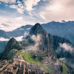 Die Ruinen von Machu Picchu, eingebettet in nebelverhangene Andengipfel. Ein atemberaubender Blick auf die Inka-Stadt, die sich an die Berghänge schmiegt.