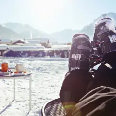 Narty i kubki kawy na śniegu w górskiej scenerii.