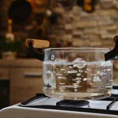 Comment avoir de l'eau chaude sans chauffe eau : une casserole en verre bout sur une cuisinière à gaz.