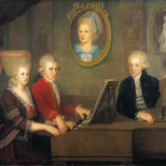 Constanze Mozart und ihre Familie musizieren. Ein Mann spielt Klavier, eine Frau sitzt daneben, ein anderer Mann hält eine Geige.