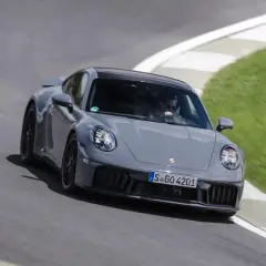 Un'auto sportiva ibrida grigia sfreccia su una pista, con il guidatore concentrato.