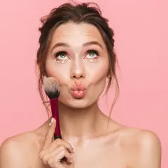 Jeune fille avec un maquillage simple et des perles sous les yeux, tenant un pinceau. Idéal pour un maquillage simple pour jeune fille.