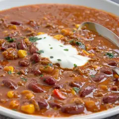 Herzhaftes Chili con Carne original mit Kidneybohnen, Mais und Hackfleisch, garniert mit einem Klecks saurer Sahne und Petersilie.